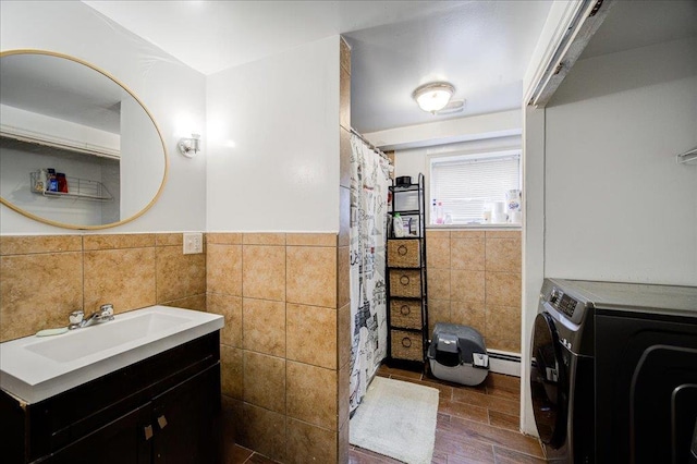 bathroom with tile walls, washer / clothes dryer, vanity, and a baseboard heating unit