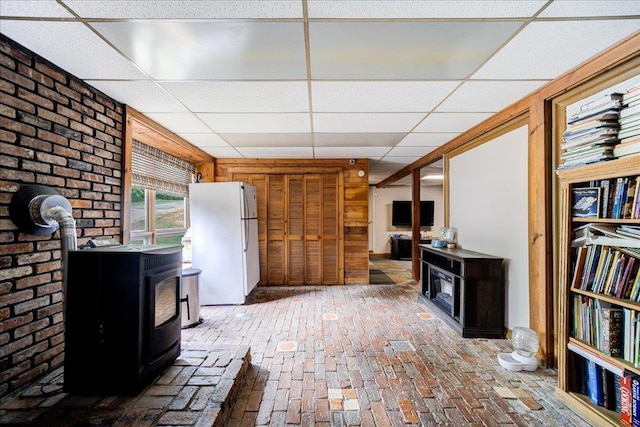 interior space with a wood stove and a drop ceiling