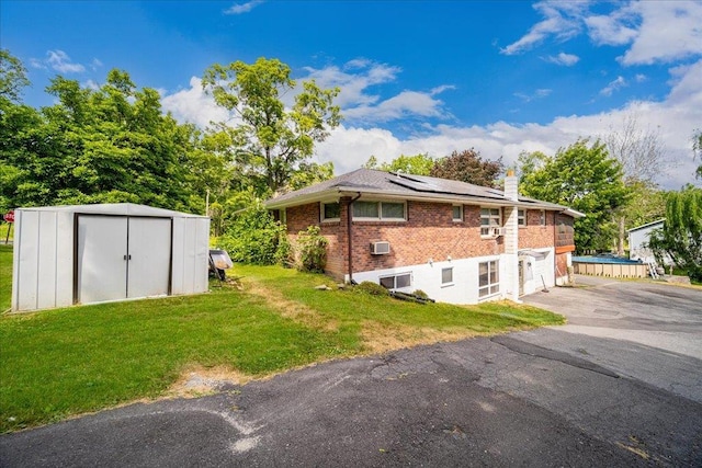 view of side of home featuring a storage shed, a lawn, and solar panels