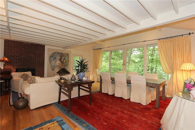 interior space with beamed ceiling, wood-type flooring, and a brick fireplace