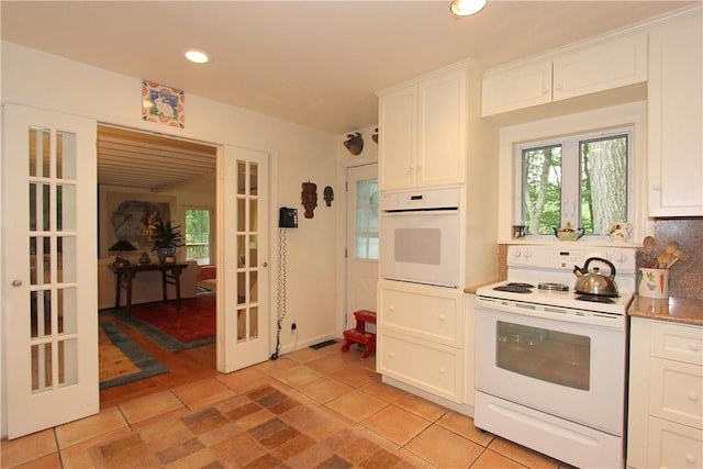 kitchen with white cabinetry, french doors, light tile patterned floors, and white appliances