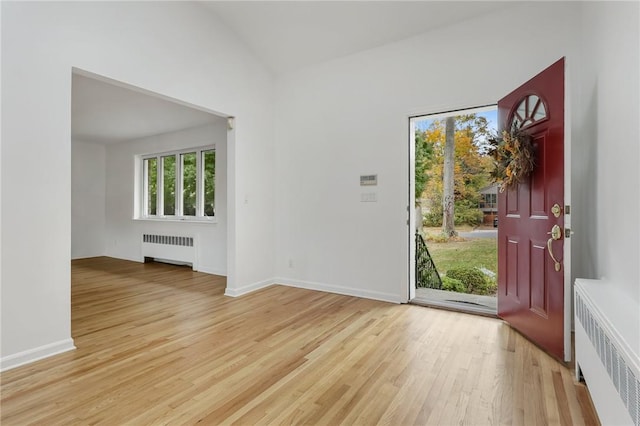 entryway featuring lofted ceiling, radiator heating unit, and light hardwood / wood-style flooring