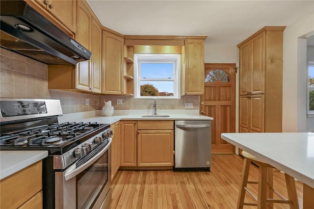 kitchen featuring decorative backsplash, light brown cabinetry, light wood-type flooring, stainless steel appliances, and sink