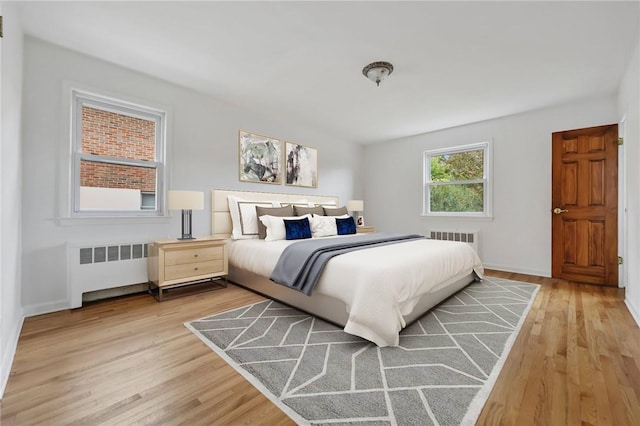 bedroom with radiator heating unit and light hardwood / wood-style flooring