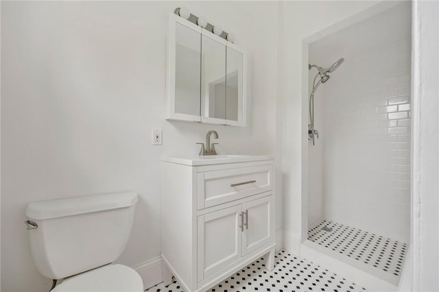 bathroom featuring tiled shower, tile patterned floors, vanity, and toilet