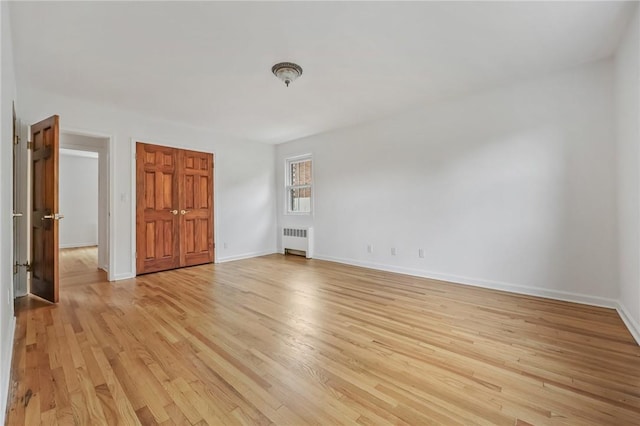 unfurnished room featuring radiator heating unit and light hardwood / wood-style flooring