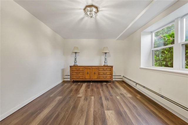 unfurnished bedroom with dark hardwood / wood-style flooring and a baseboard heating unit