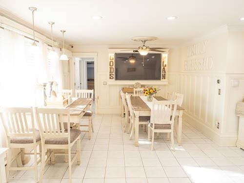 tiled dining space with ceiling fan and crown molding