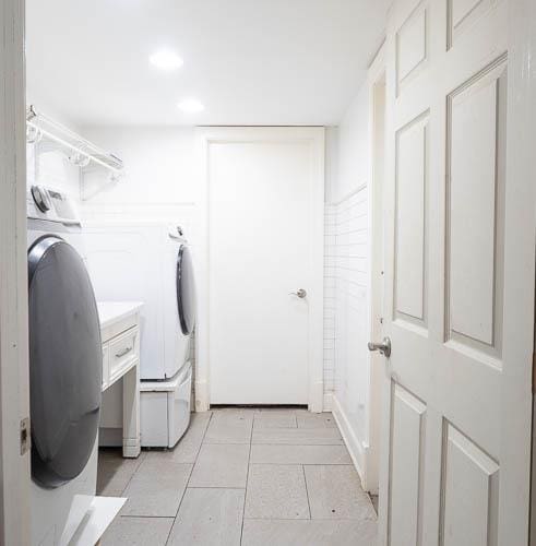 clothes washing area featuring light tile patterned flooring and separate washer and dryer