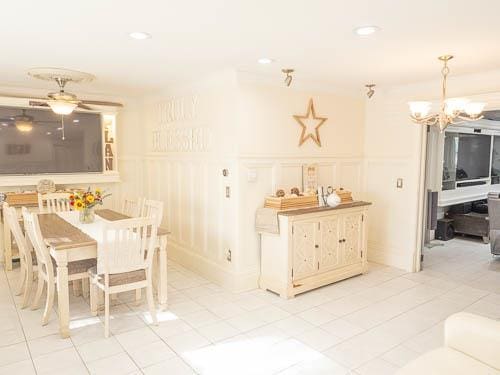 dining space with light tile patterned flooring and ceiling fan with notable chandelier