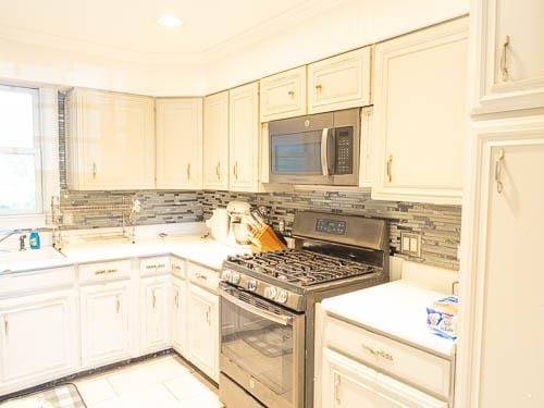 kitchen featuring decorative backsplash, sink, stainless steel appliances, and ornamental molding