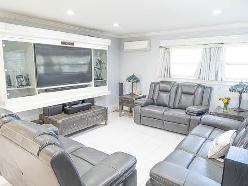 living room with a wall unit AC and ornamental molding