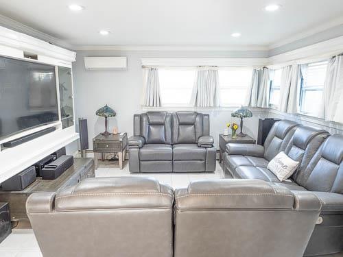 tiled living room featuring a wall mounted AC and crown molding