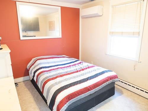 bedroom with a wall mounted air conditioner and a baseboard heating unit