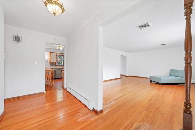 corridor featuring light wood-type flooring and a baseboard heating unit