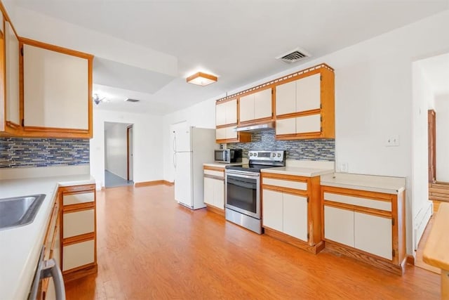 kitchen with white cabinets, appliances with stainless steel finishes, light hardwood / wood-style floors, and decorative backsplash