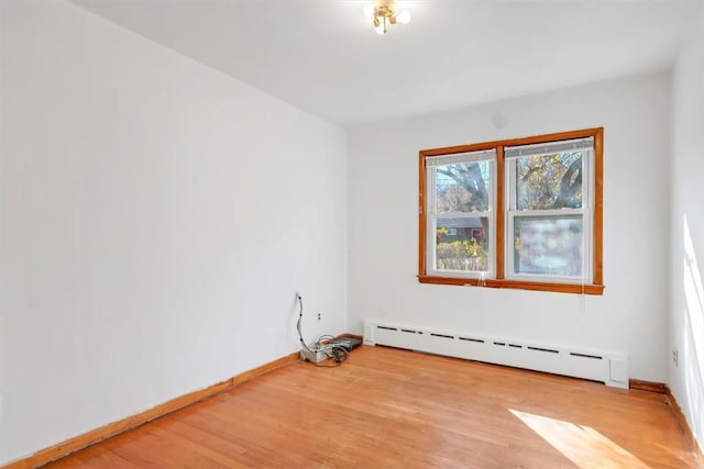 empty room with light wood-type flooring and a baseboard heating unit