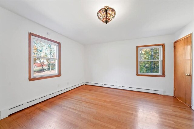 empty room featuring a baseboard radiator and light hardwood / wood-style flooring