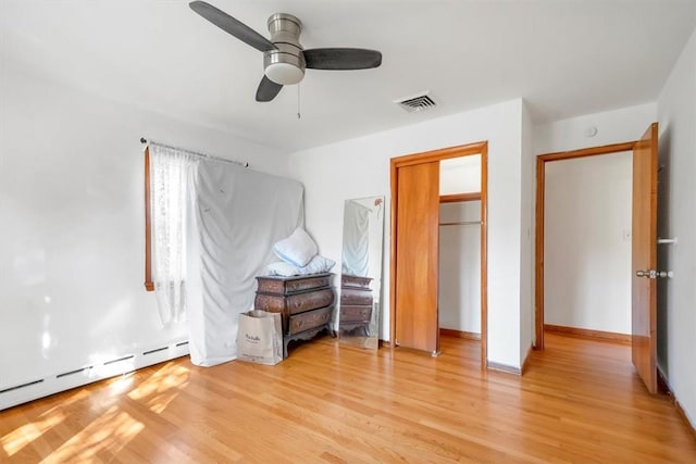 unfurnished bedroom featuring a closet, a baseboard radiator, light hardwood / wood-style flooring, and ceiling fan