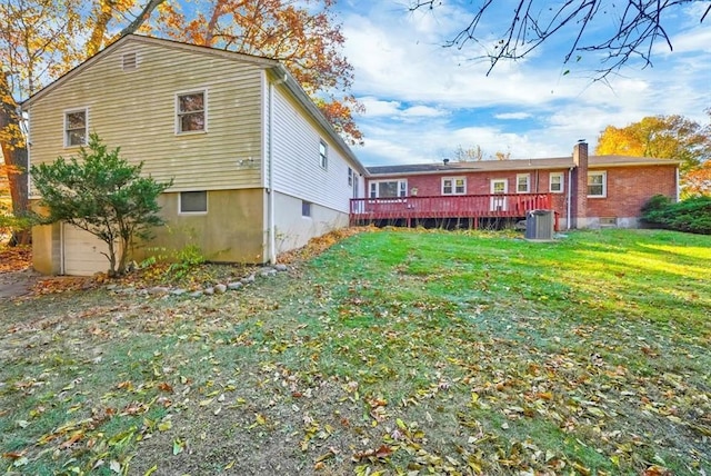 rear view of house with central AC unit, a yard, and a wooden deck