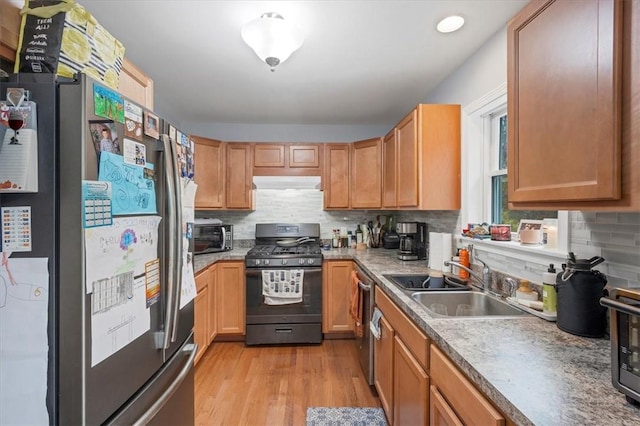 kitchen with sink, backsplash, black appliances, and light wood-type flooring