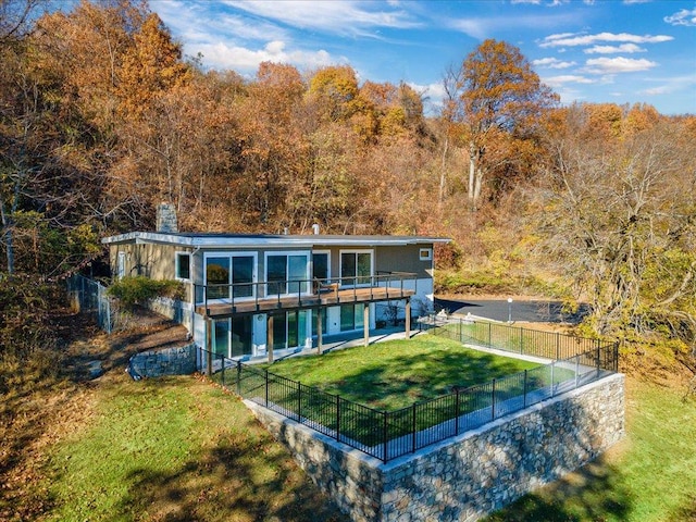 rear view of property with a wooden deck, a patio area, and a lawn