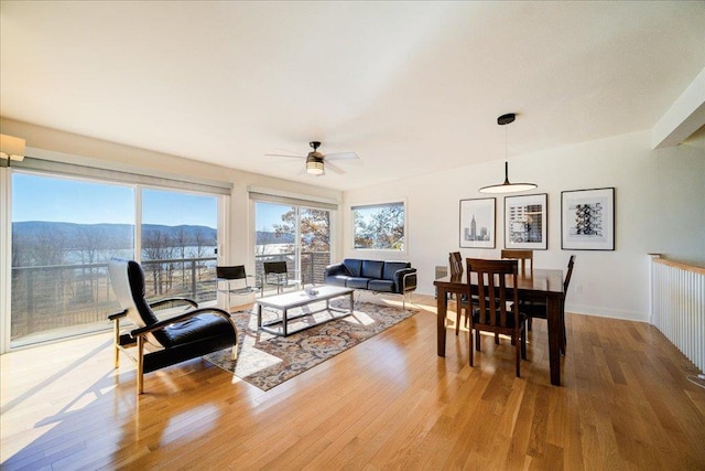 living room with a mountain view, wood-type flooring, and ceiling fan