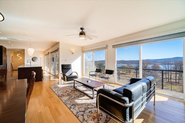 living room with light hardwood / wood-style flooring, ceiling fan, and sink