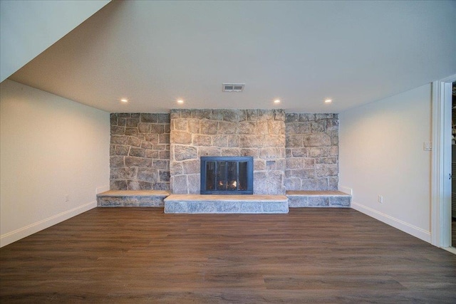 unfurnished living room with a stone fireplace and dark wood-type flooring