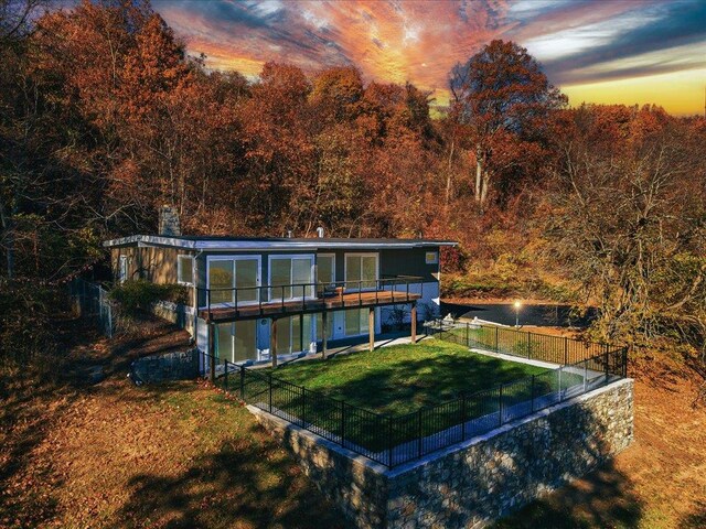 back house at dusk featuring a yard, a water view, and a patio