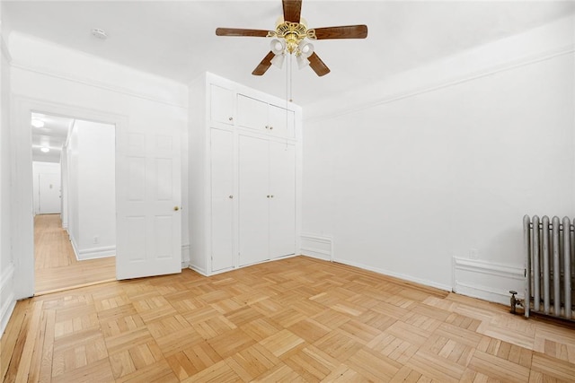 unfurnished bedroom featuring radiator heating unit, a closet, light parquet floors, and ceiling fan