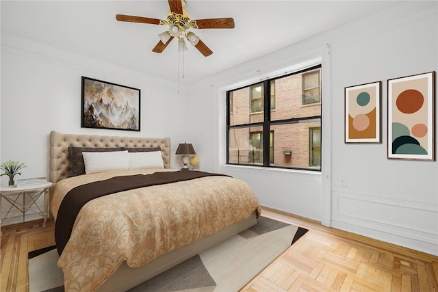 bedroom with light parquet floors, ceiling fan, and ornamental molding