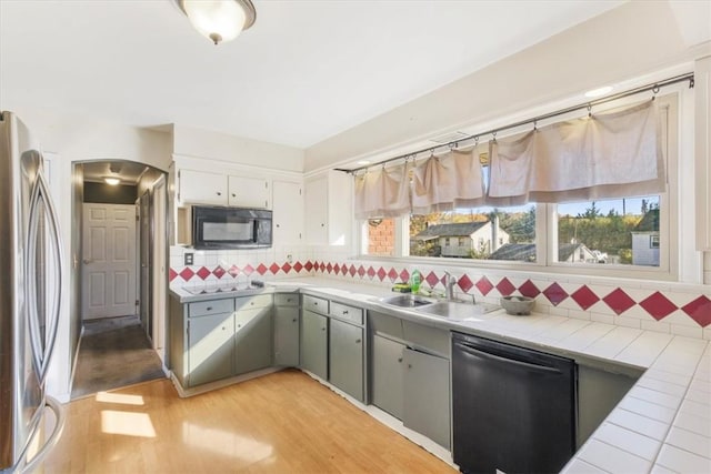 kitchen featuring tile counters, sink, stainless steel appliances, tasteful backsplash, and light wood-type flooring