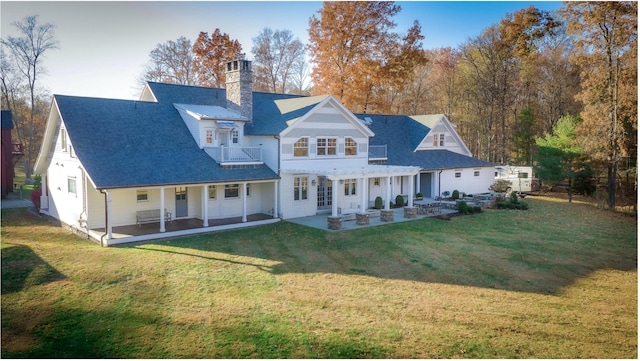 rear view of house featuring a pergola, a balcony, a patio area, and a lawn