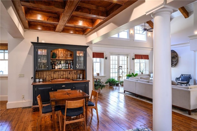 bar featuring ornate columns, wood ceiling, ceiling fan, dark wood-type flooring, and beam ceiling