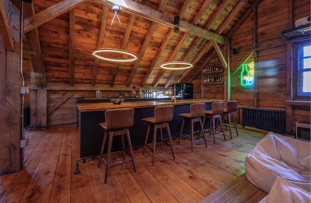 bar with radiator, lofted ceiling with beams, wooden ceiling, butcher block counters, and wood walls