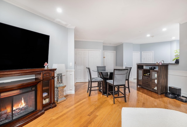 dining space with ornamental molding and light hardwood / wood-style flooring