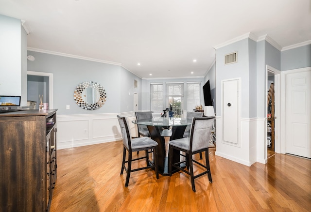 dining area featuring ornamental molding and light hardwood / wood-style floors