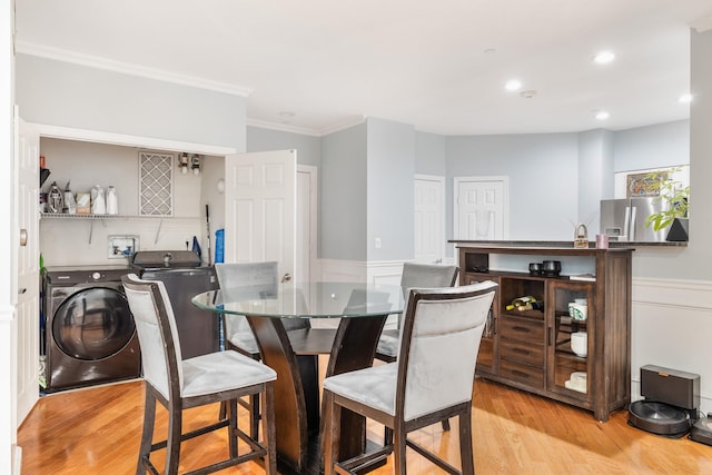 dining area with ornamental molding, light hardwood / wood-style floors, and independent washer and dryer