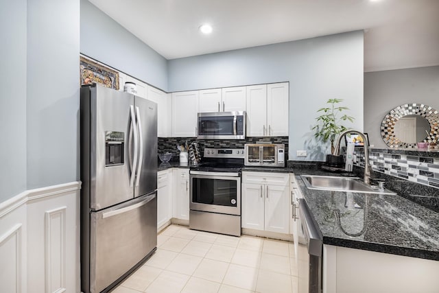 kitchen with sink, appliances with stainless steel finishes, dark stone countertops, white cabinets, and decorative backsplash