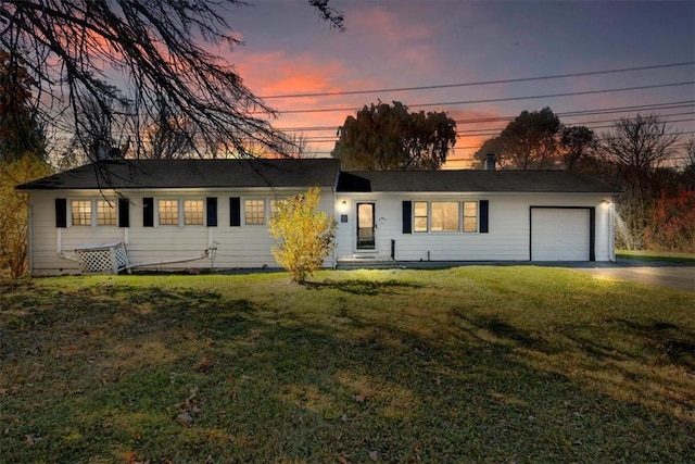 ranch-style house with a garage and a lawn