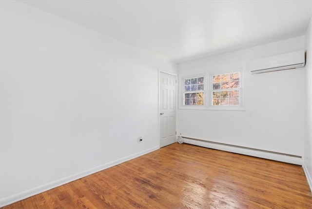 unfurnished room with a wall mounted air conditioner, hardwood / wood-style floors, and a baseboard heating unit