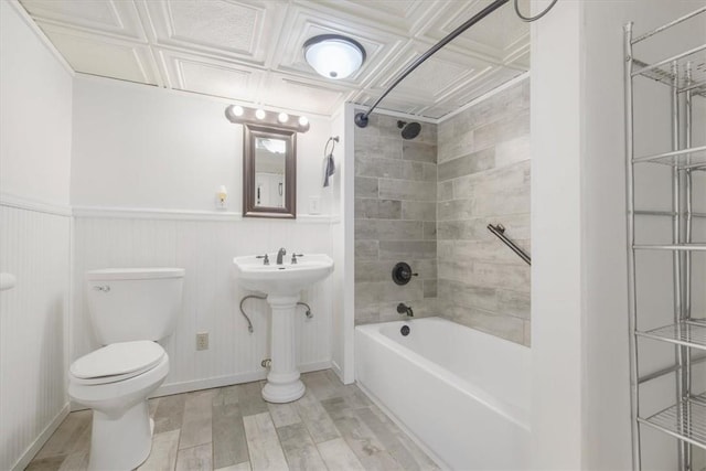 bathroom with hardwood / wood-style floors, toilet, and tiled shower / bath