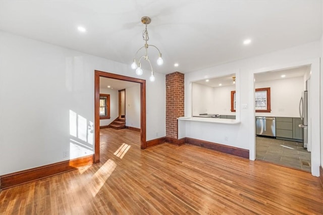 unfurnished living room with hardwood / wood-style floors and an inviting chandelier