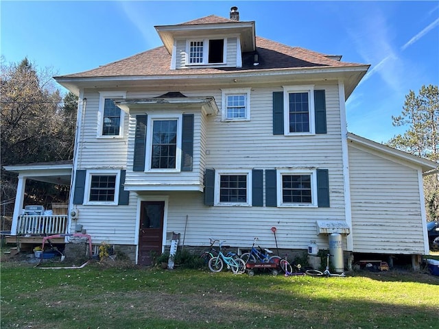 rear view of property featuring a lawn and roof with shingles