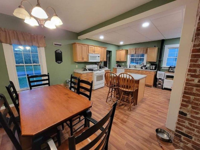dining area featuring light wood-style flooring, recessed lighting, beamed ceiling, and a chandelier