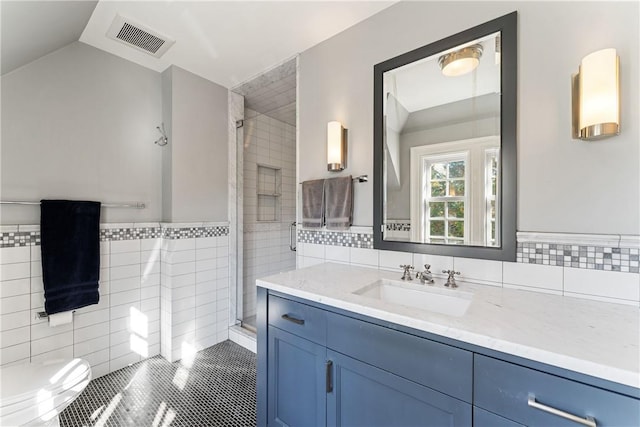 bathroom featuring tile patterned floors, vanity, a shower with door, tile walls, and lofted ceiling