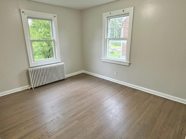 unfurnished room with radiator heating unit and dark wood-type flooring