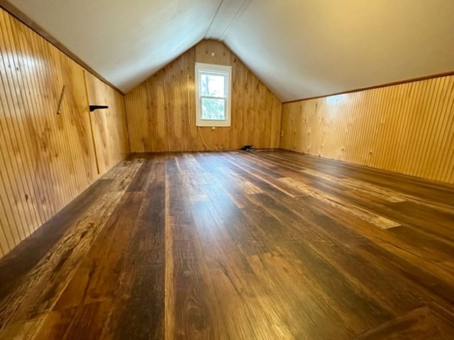 additional living space with wooden walls, dark wood-type flooring, and lofted ceiling