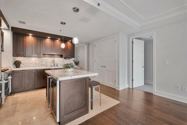 kitchen featuring a breakfast bar, a center island, hanging light fixtures, dark brown cabinets, and light hardwood / wood-style floors